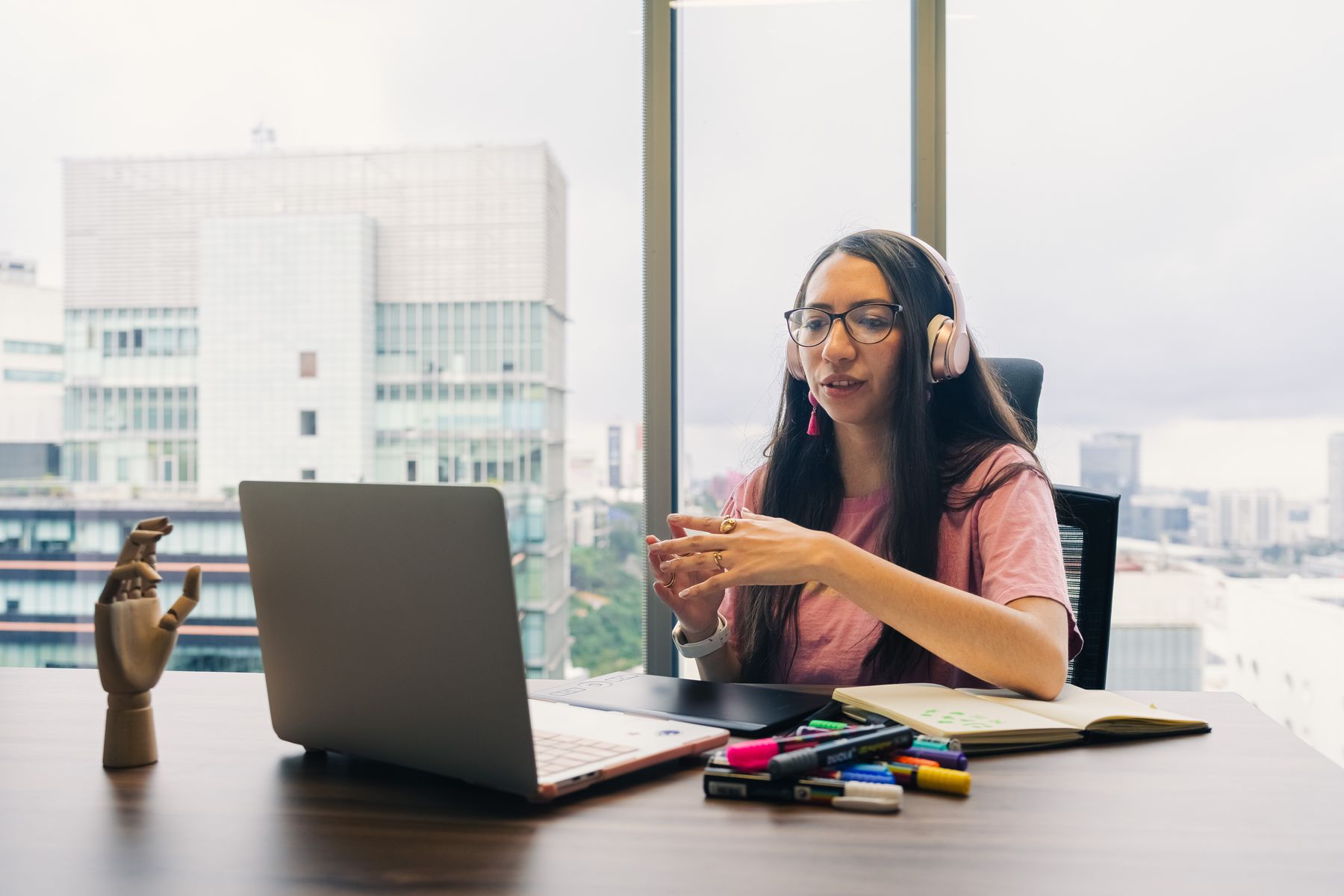 A young woman in a headset talking on a video call at her laptop