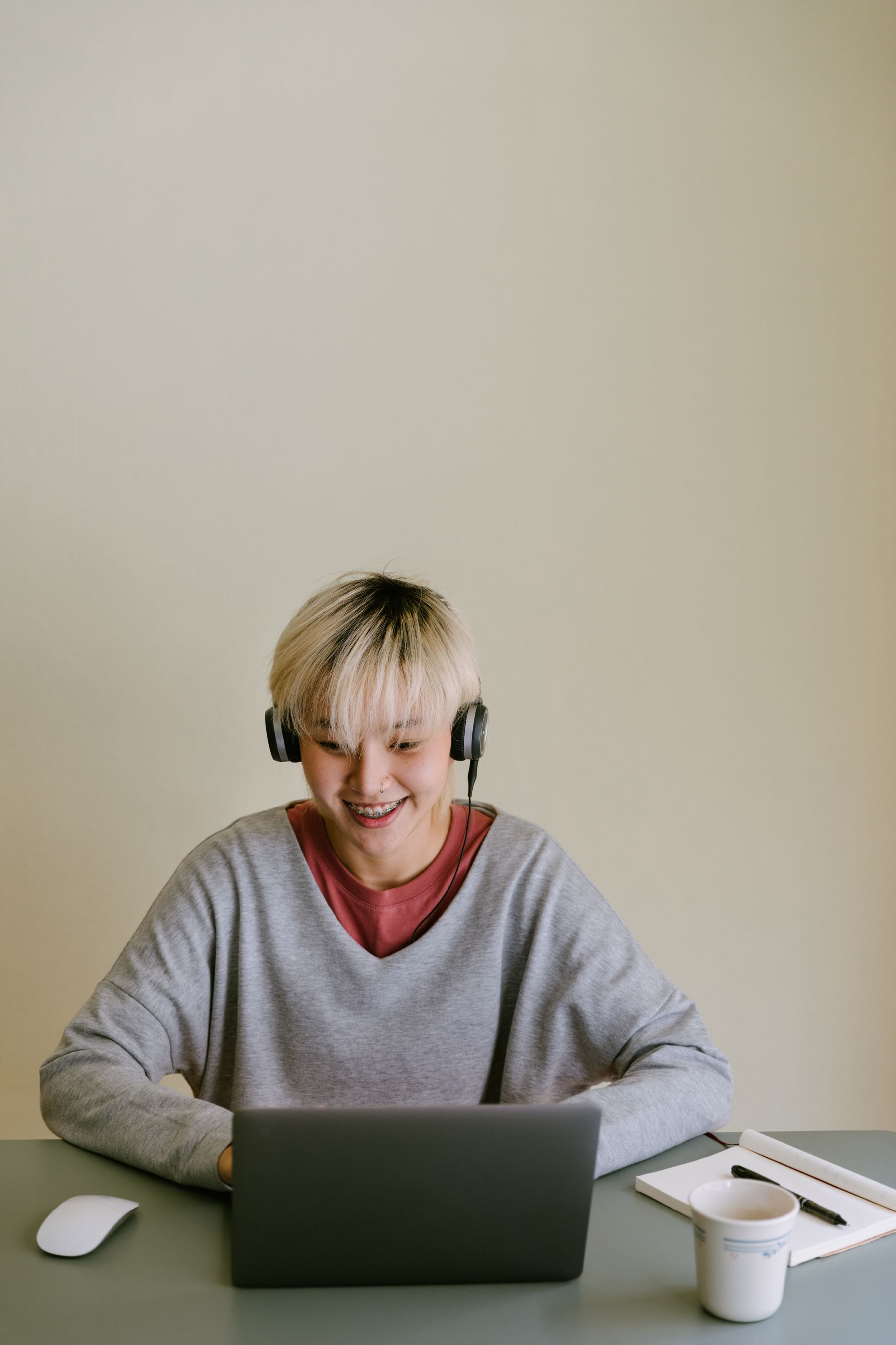 A smiling young person in headphones on a laptop call
